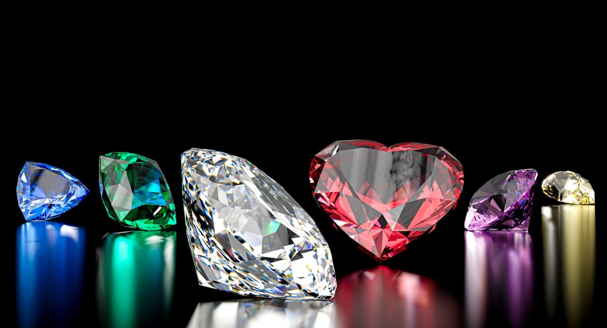 Colorful gemstones including a red heart diamond on a black surface